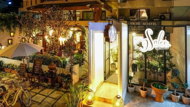 Un hostal con un letrero que dice "Salfe Hostel" y una entrada bien iluminada con plantas en macetas y una bicicleta.