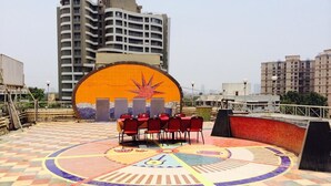 Terraza en la azotea con escenario, asientos y un diseño de suelo colorido.