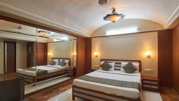 Un dormitorio con una cama grande, mesitas de noche, un espejo y un ventilador de techo.