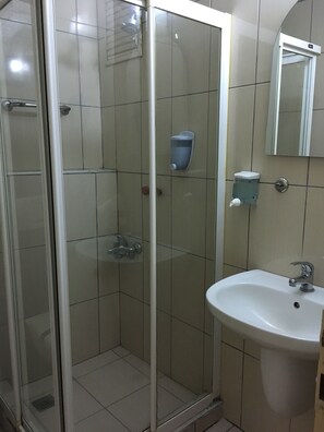 Une salle de bain avec une douche à parois de verre, un lavabo et un miroir.