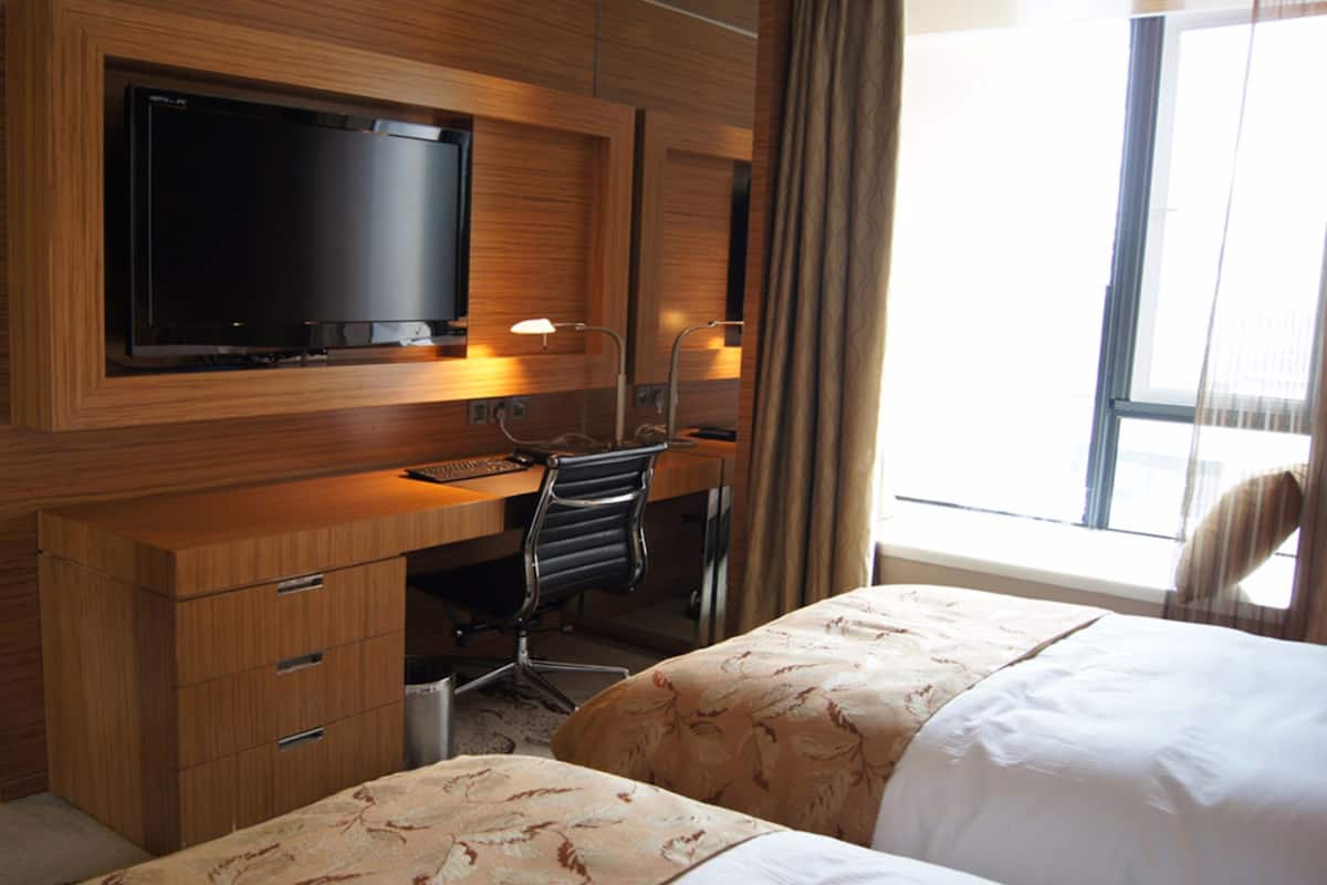 Ein Hotelzimmer mit einem Holztisch, einem Fernseher, einem Sessel und einem Bett.