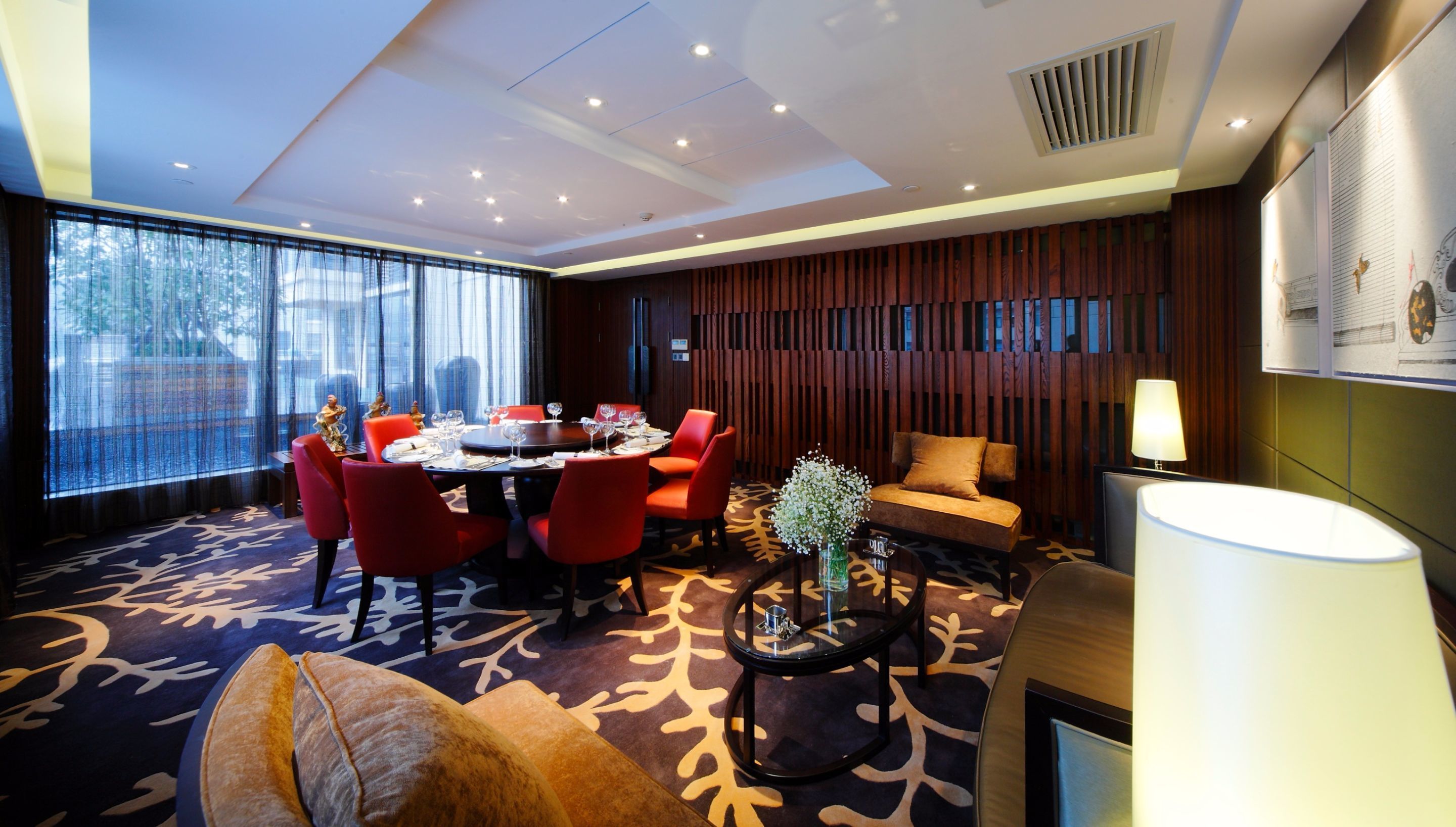 Une chambre d’hôtel avec un coin repas, un canapé et une lampe.
