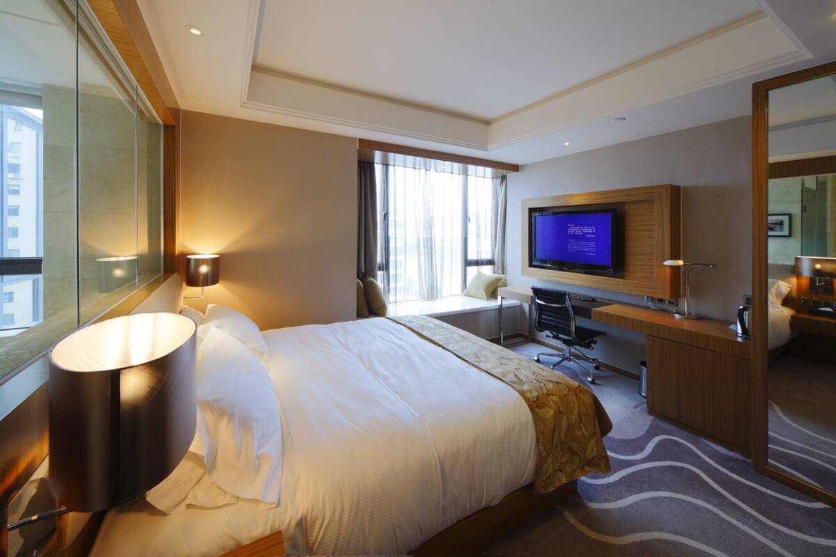 Ein Hotelzimmer mit Bett, Schreibtisch, Fernseher und Badezimmer.