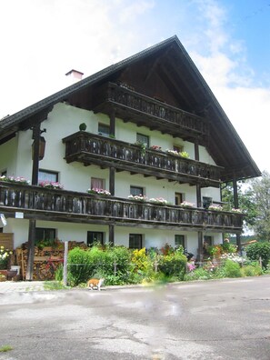 A traditional multi-story building with balconies, wooden railings, and flower boxes.