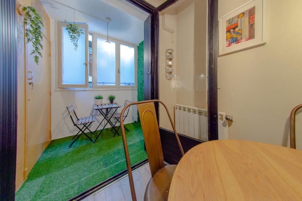 A compact room with a small table and two chairs, a radiator, and a window with frosted glass.