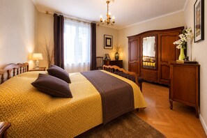 Un dormitorio con una cama grande, un armario de madera, un escritorio y una araña.