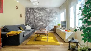 A modern living room with a sofa, coffee table, and TV. - Le Rétro Mirabeau - Maison de Famille (Narbonne)