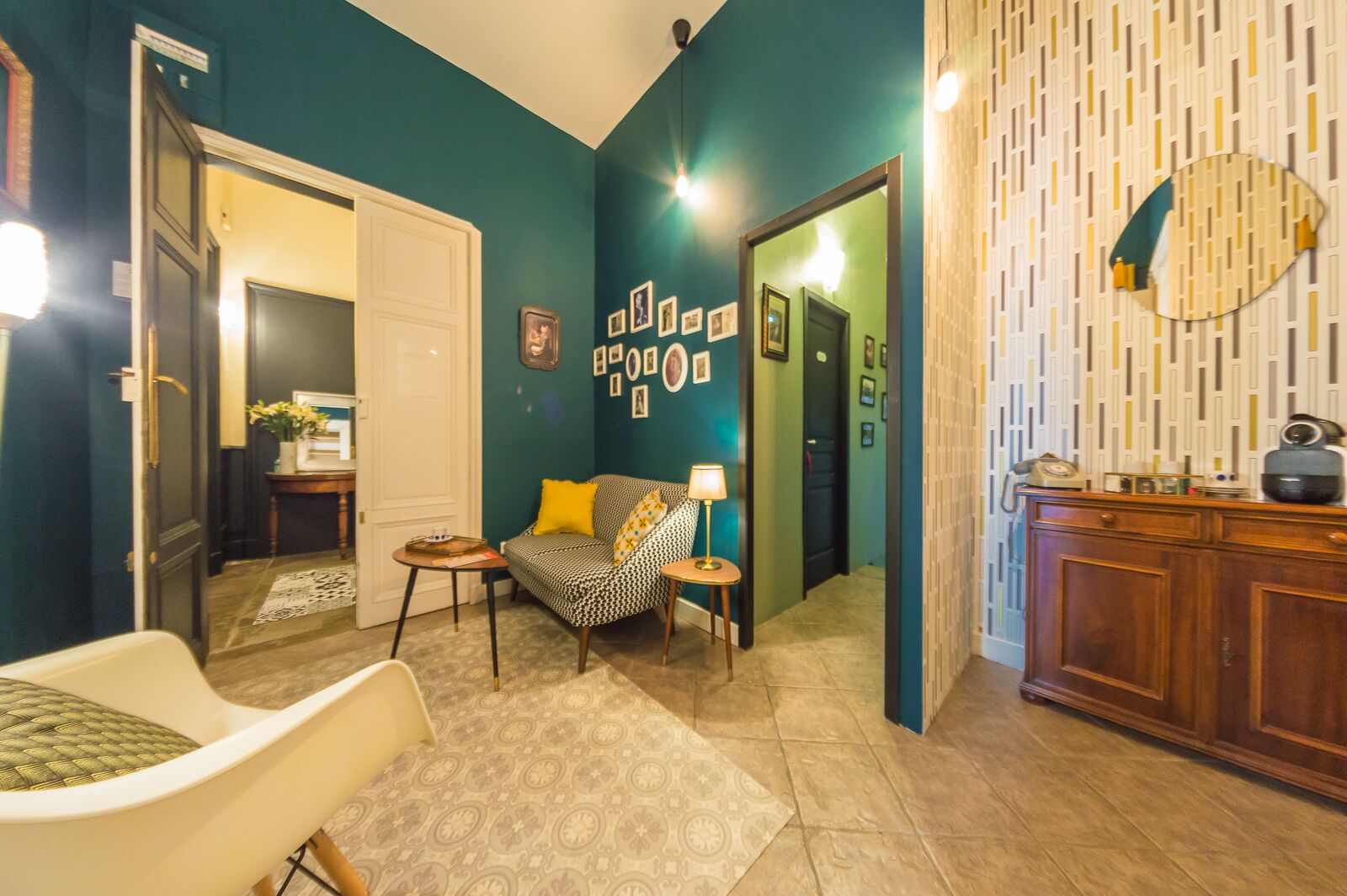 A living room with teal walls, a sofa with yellow cushions, a coffee table, and a wooden cabinet with a mirror.