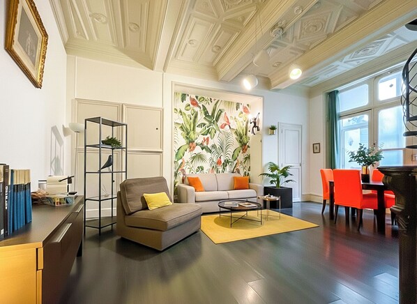 A living room with a sofa, coffee table, bookshelf, and a large window with a view.