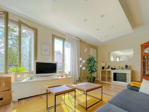 A modern living room with a flat-screen TV, a sofa, a coffee table, and a fireplace.