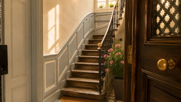 A staircase with a wooden handrail and a patterned floor. - Le Rétro Mirabeau - Maison de Famille (Narbonne)