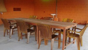 A dining area with a long wooden table surrounded by plastic chairs. - Mystique Highland Resort (Pokhara)