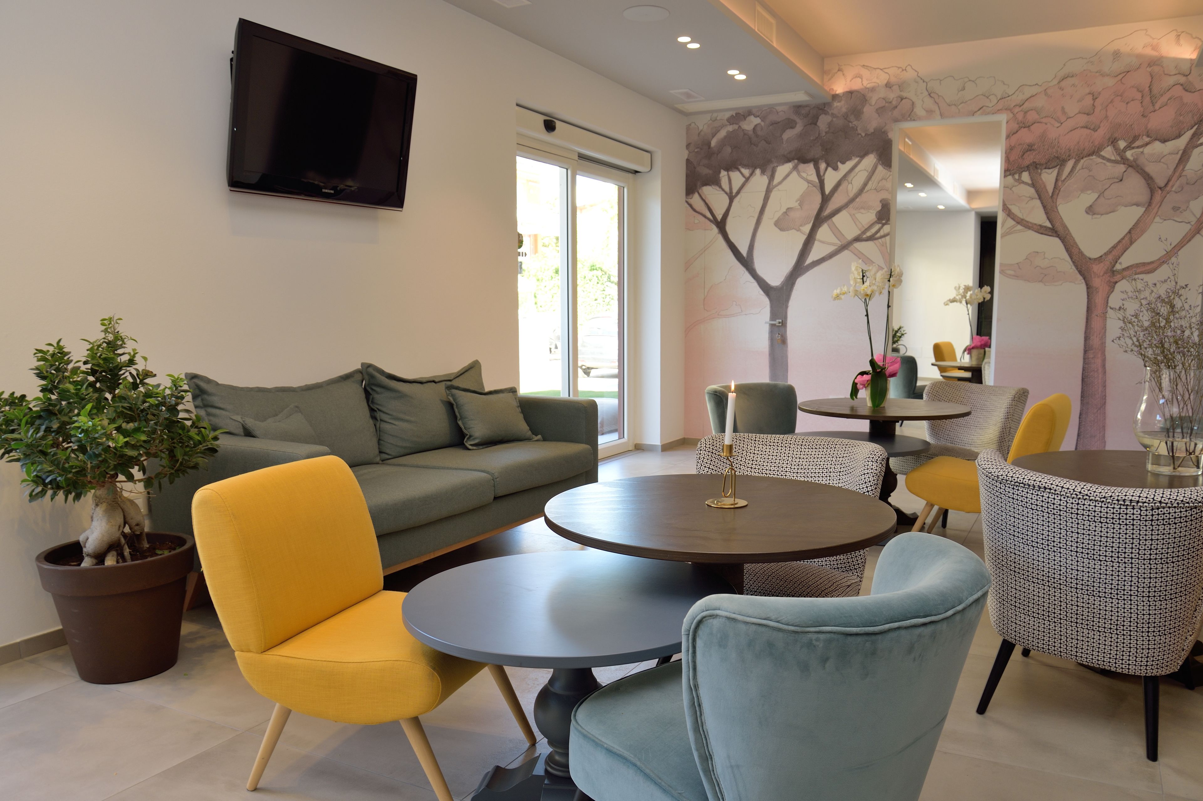 Uma sala de estar moderna com sofá, poltronas amarelas, mesa redonda e planta em vaso.