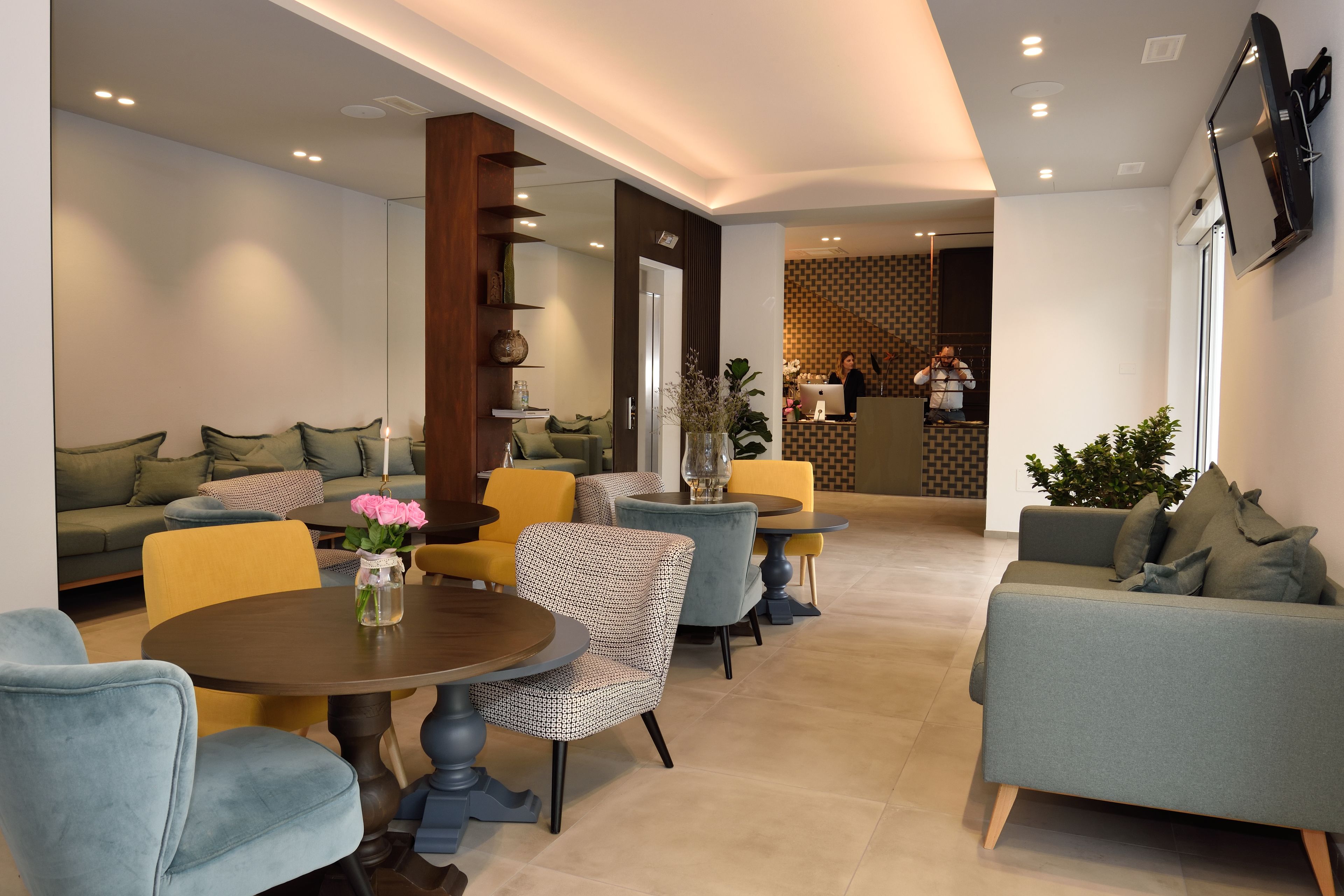 Un espace de détente moderne, doté de canapés, de fauteuils et de tables, avec une table basse centrale agrémentée de fleurs.