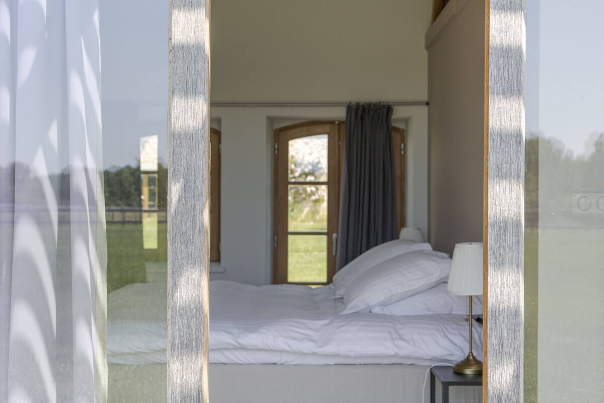 Une chambre à coucher avec un lit, une fenêtre et une table de chevet avec une lampe.