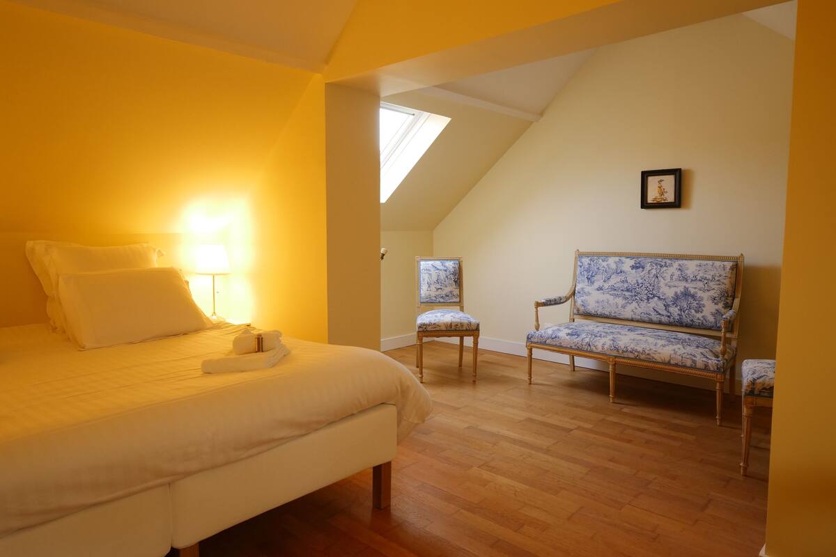 Une chambre à coucher avec un lit, une chaise et une lampe.