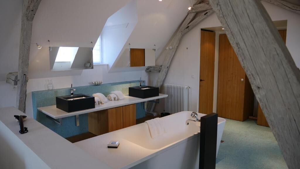 A modern bathroom with a large bathtub, a double sink, and a mirror above the sink.