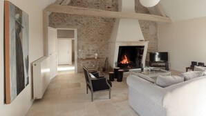 Un salon spacieux avec une cheminée, un canapé, une table basse et un tableau accroché au mur.
