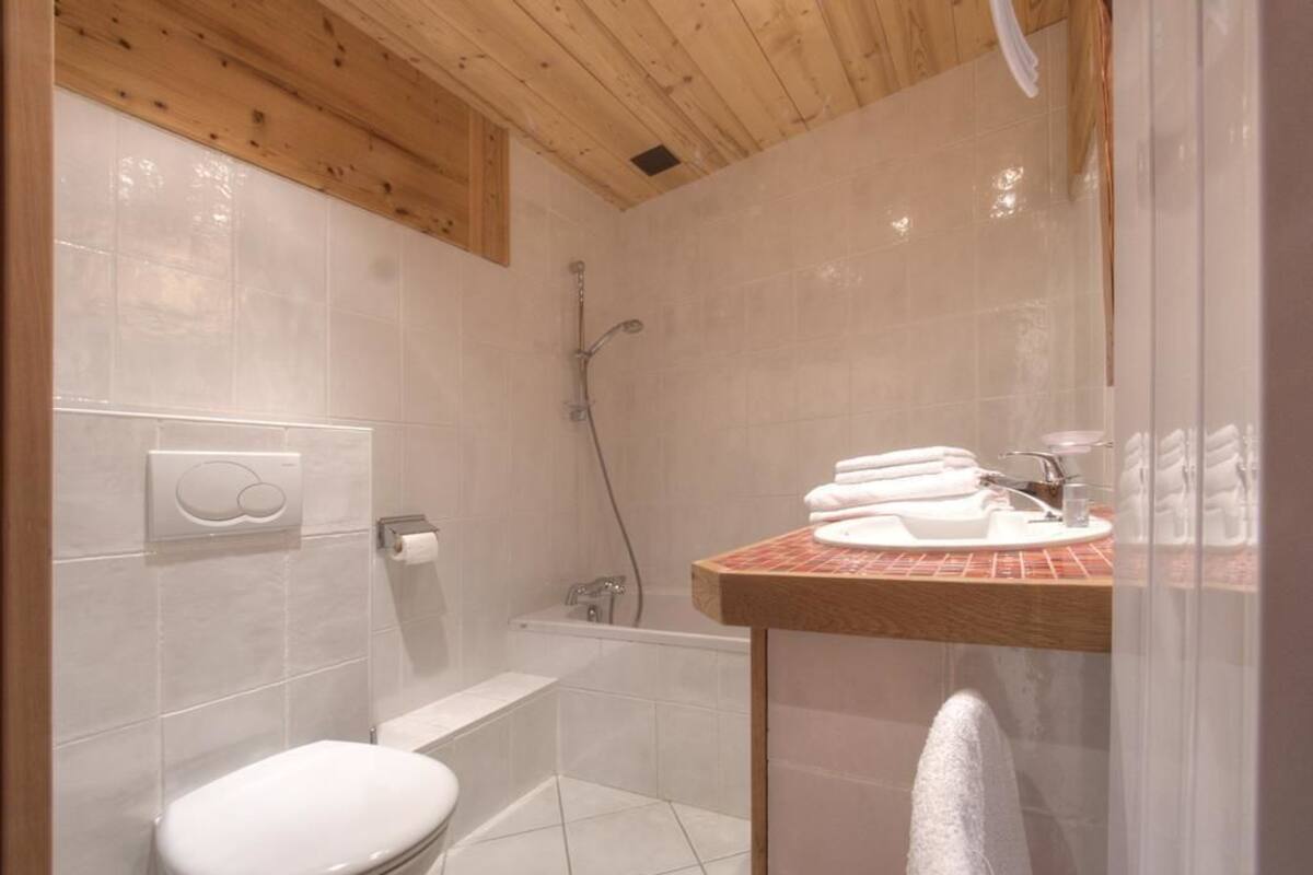 A small bathroom with a toilet, a shower, and a sink with a towel rack.
