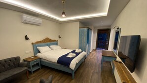 A bedroom with a bed, a chair, a desk, and a TV. - Ekin Pansiyon (Demre)