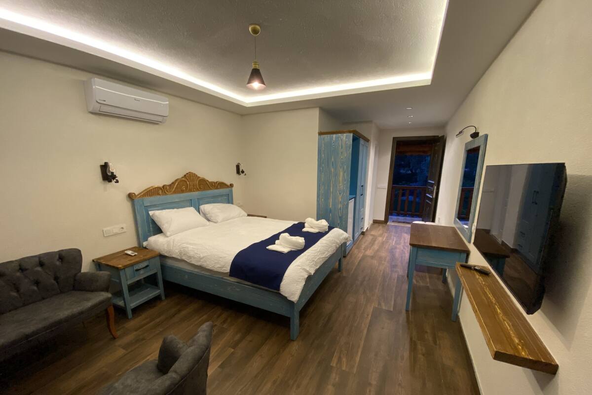 A bedroom with a bed, a chair, a desk, and a TV.