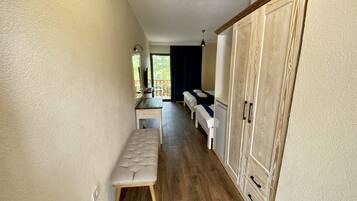 Un couloir avec un banc, une armoire en bois et un bureau doté d’un miroir et d’un téléviseur.