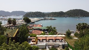 A coastal marina with boats docked, a restaurant with outdoor seating, and a mountainous backdrop. - Ekin Pansiyon (Demre)
