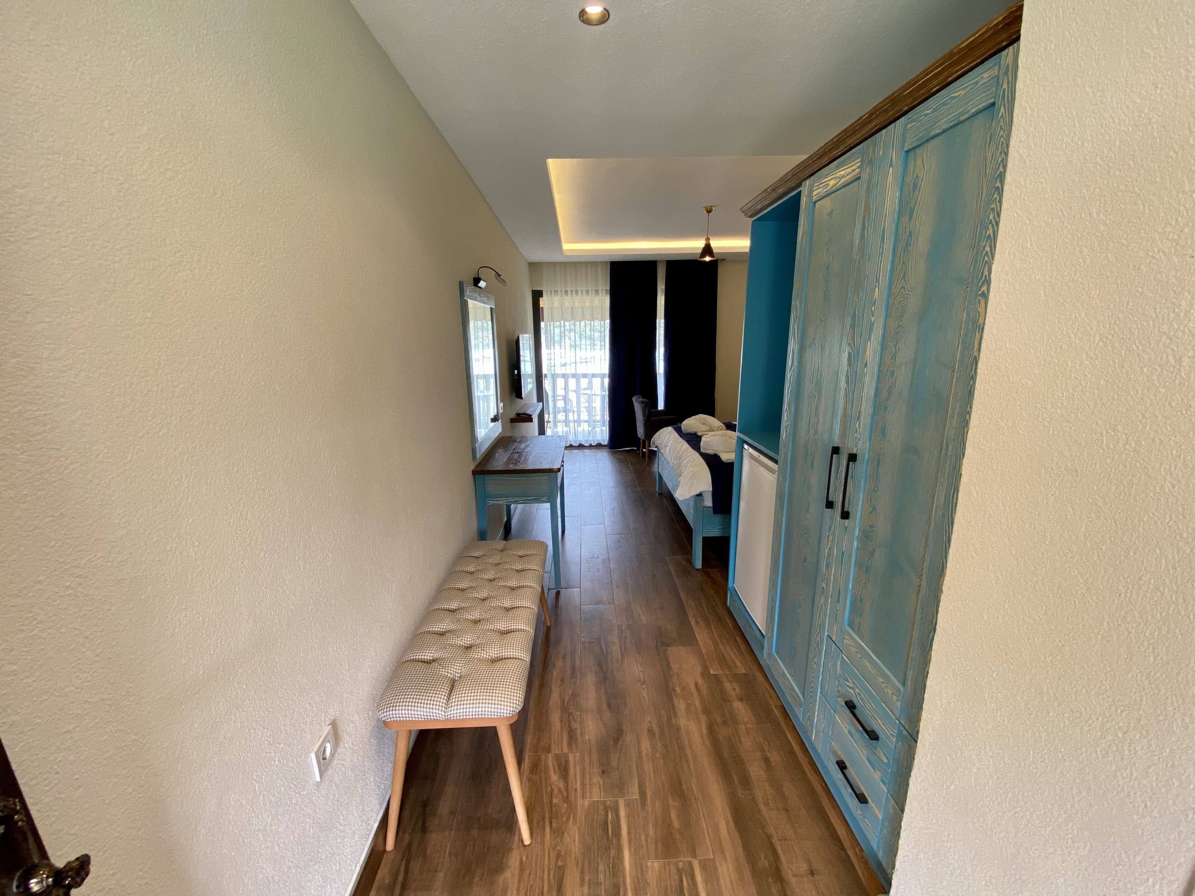 A narrow hallway with a bench, a bed, and a wardrobe.