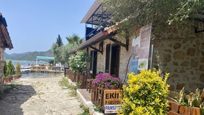 A stone building with a wooden porch, a sign for 'EKIN PANSIYOR', and a view of boats on the water. - Ekin Pansiyon (Demre)