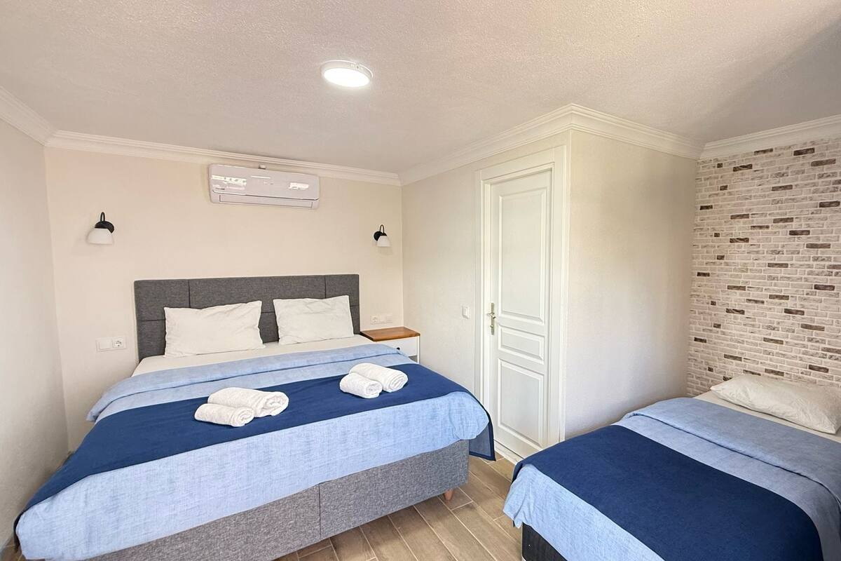 A bedroom with two beds, a white wardrobe, and a brick-patterned wall.