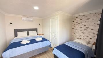 A bedroom with two beds, a white wardrobe, and a brick-patterned wall.
