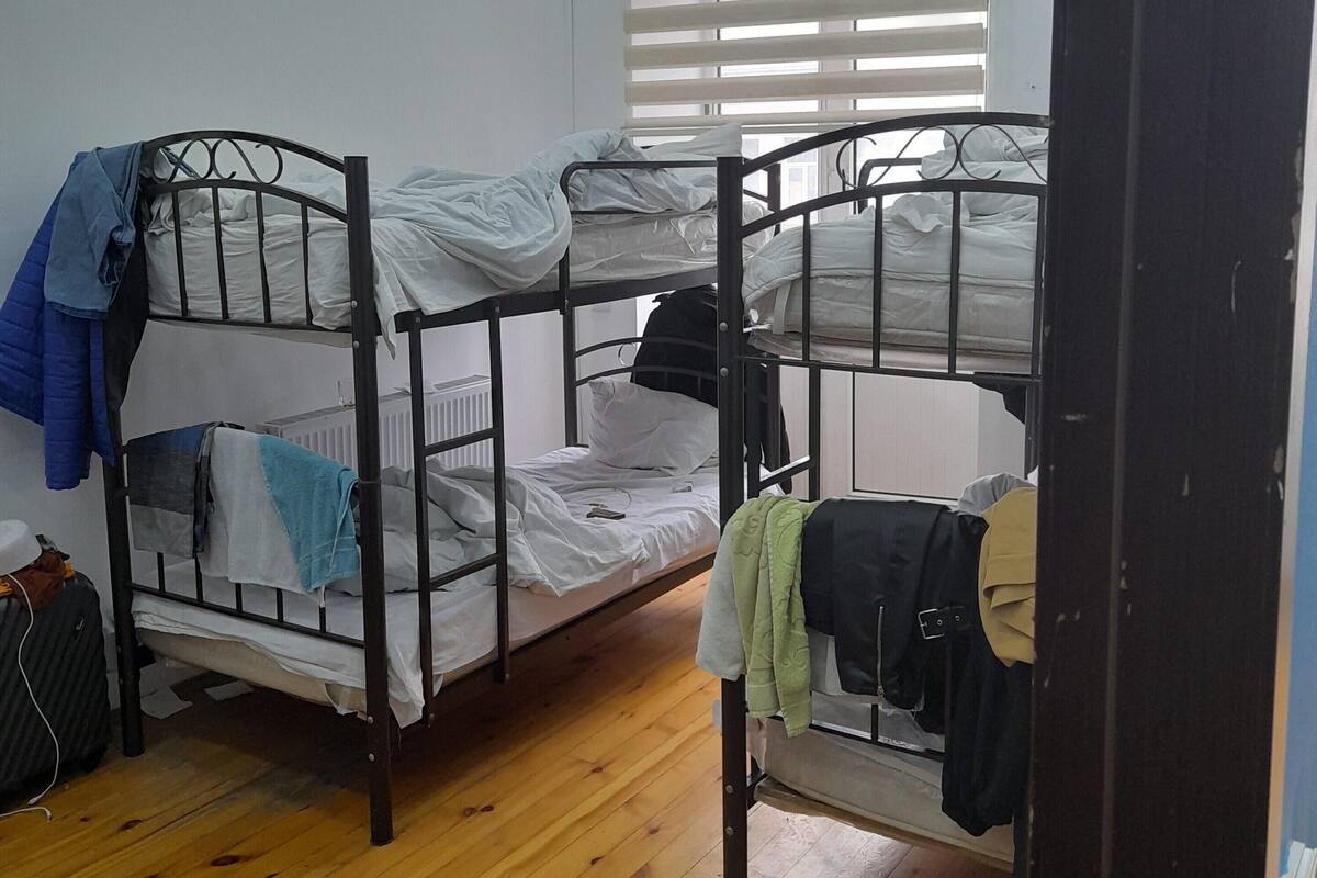 Un dormitorio con dos literas, suelo de madera, un radiador y una ventana con persianas.