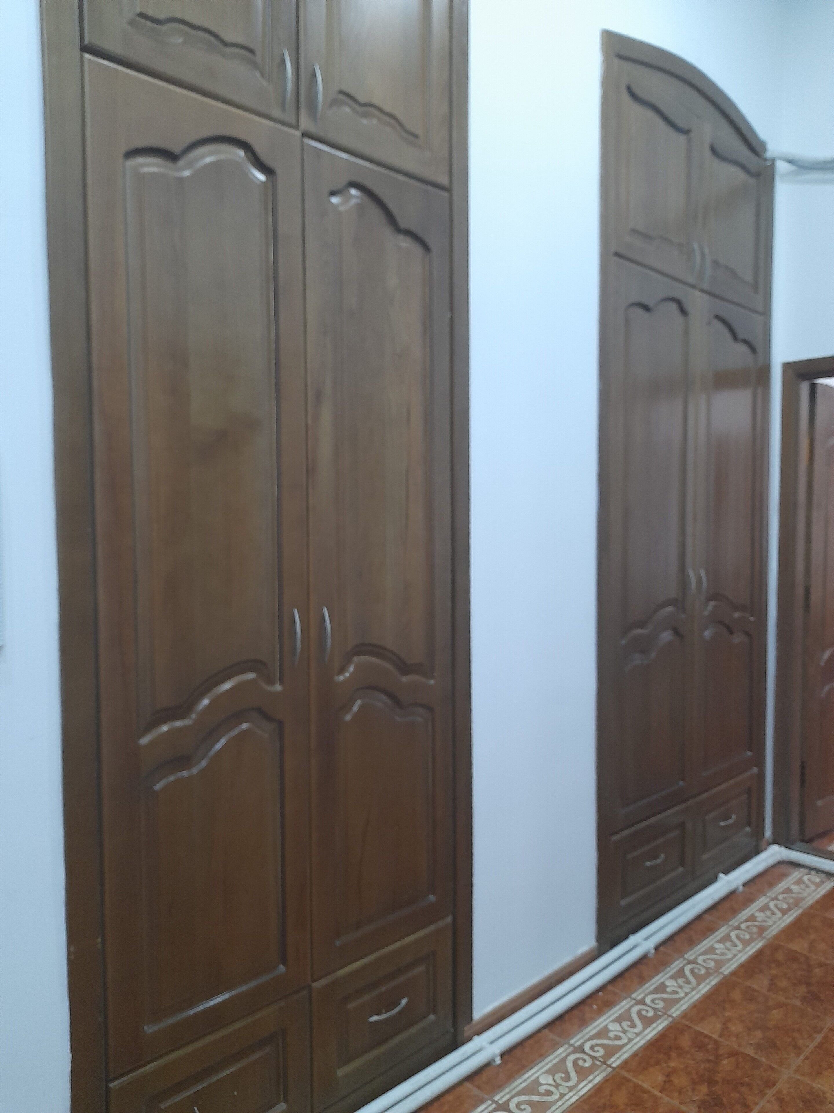 A hallway with wooden wardrobes and a patterned floor.