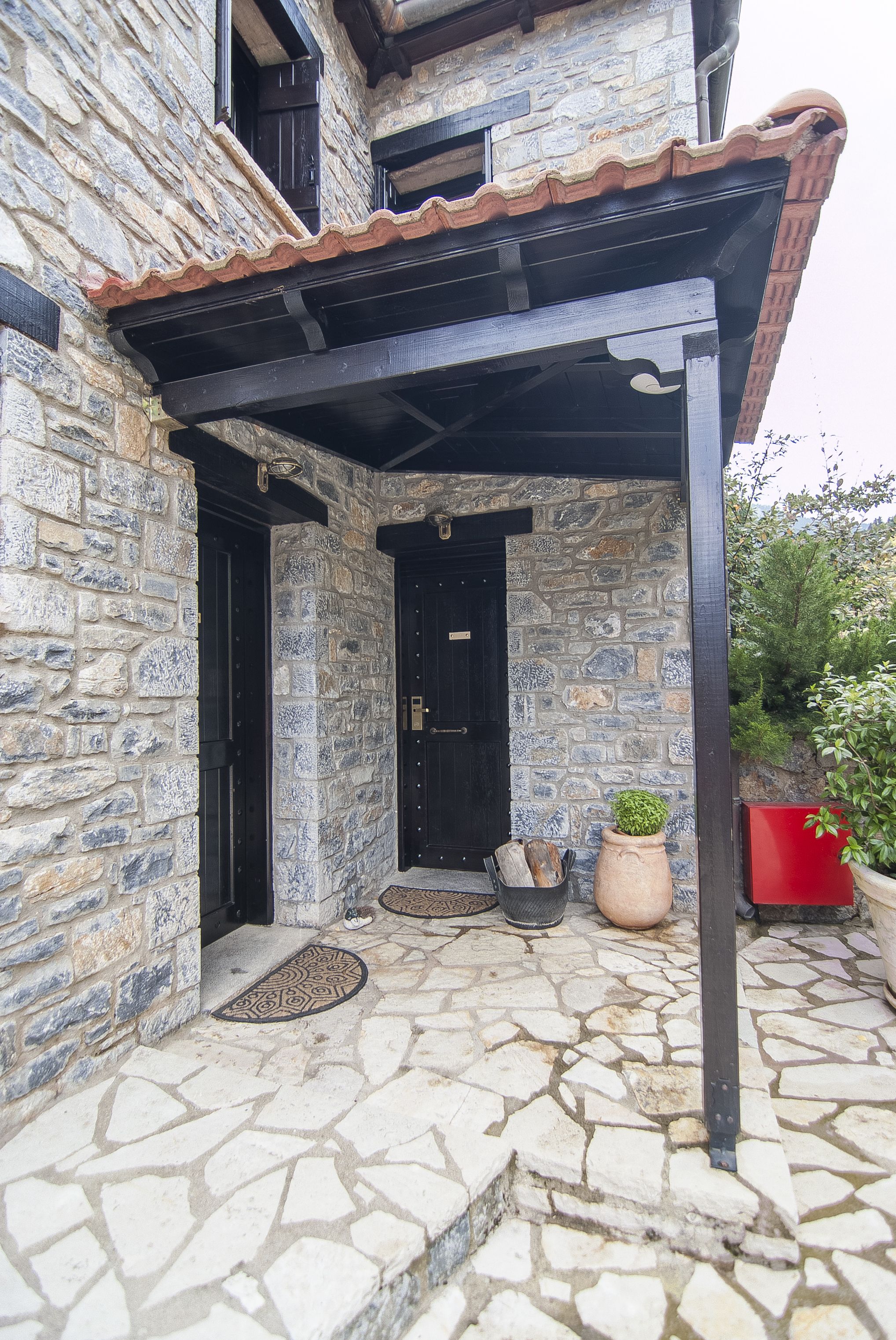 A stone building with a tiled roof, a black door, and a stone-paved entrance.