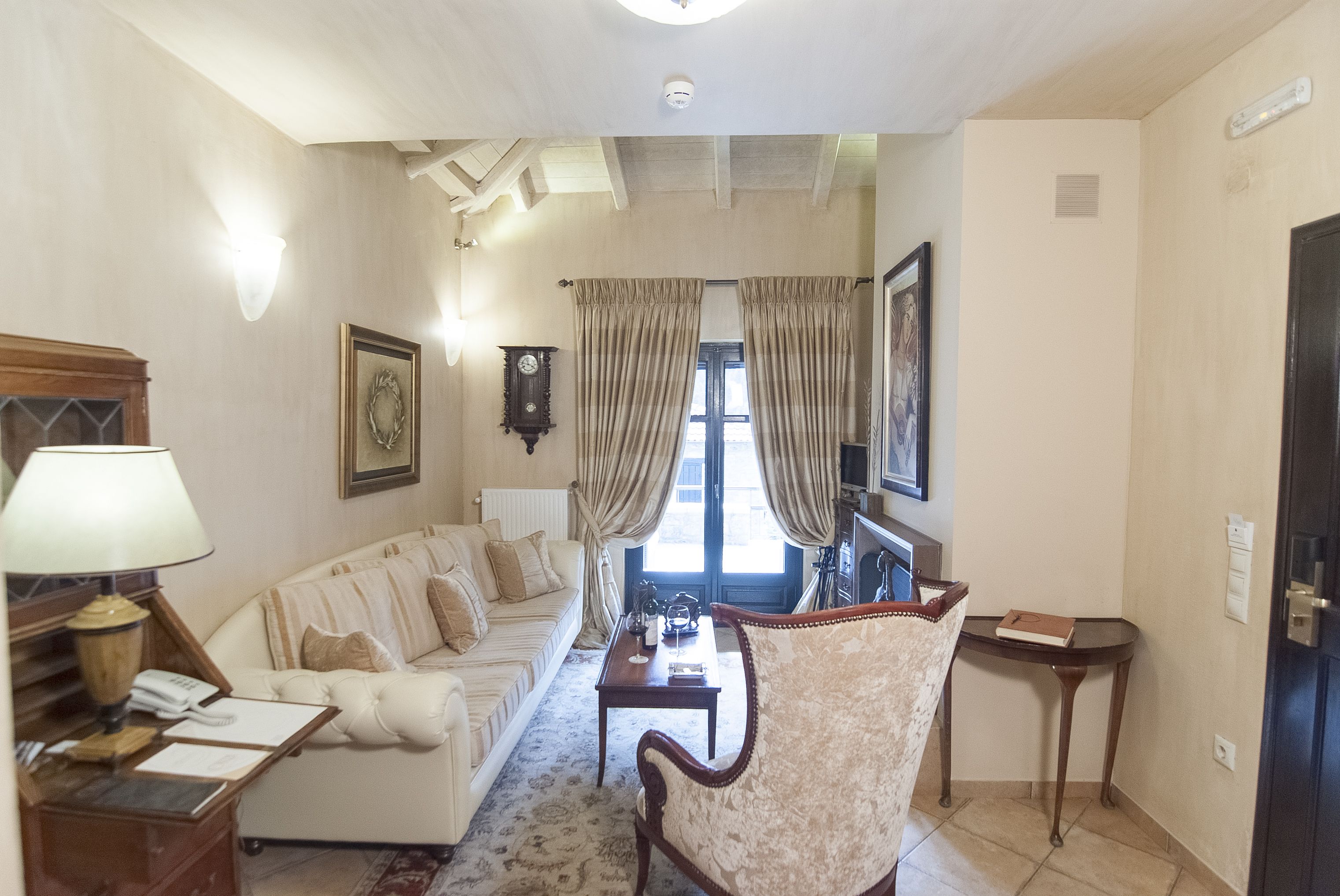 Un salón con sofá, sillón, mesa, lámpara y vistas al exterior a través de una ventana.