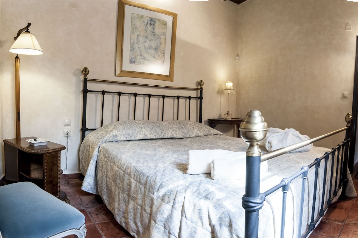 A bedroom with a bed, bedside tables, a lamp, and a painting on the wall.