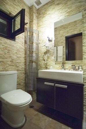 A bathroom with a white toilet, a sink with a mirror, and a towel rack.