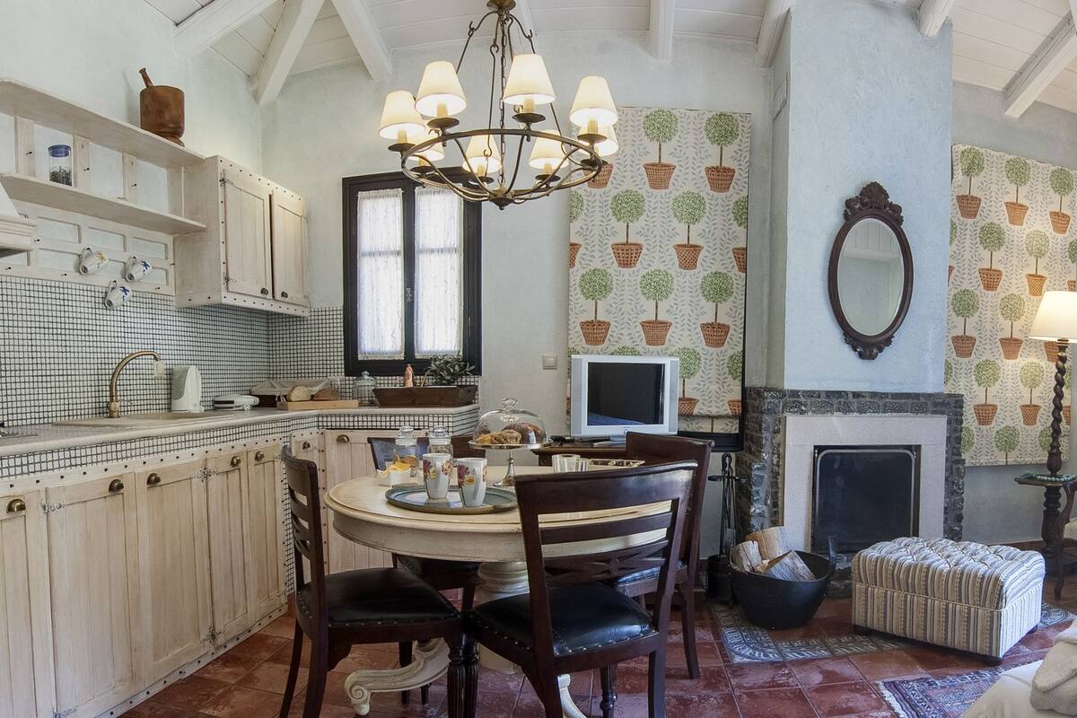A room with a dining area, a fireplace, a bed, and a view of the outdoors.