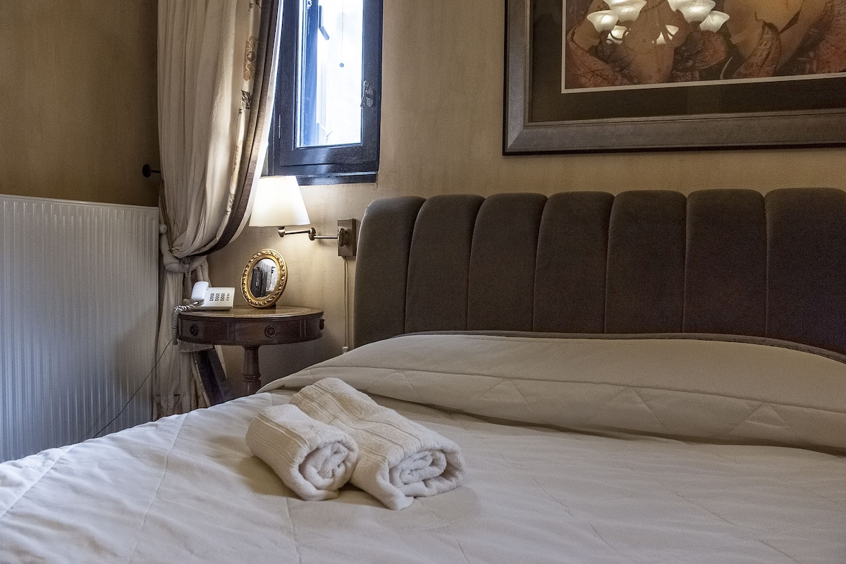 A neatly made bed with a folded towel, a bedside lamp, and a framed picture on the wall.