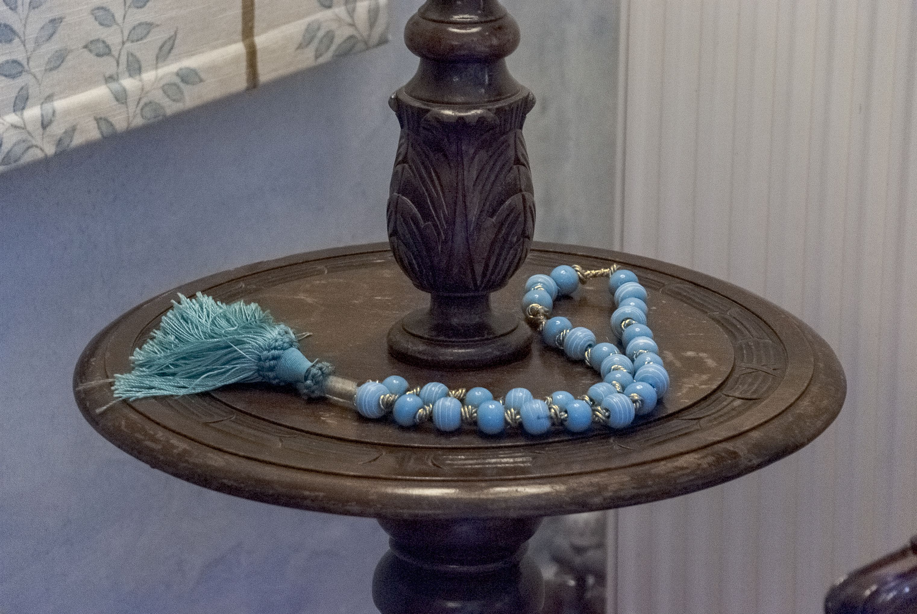 Un objet décoratif agrémenté d’une frange et posé sur un socle rond.