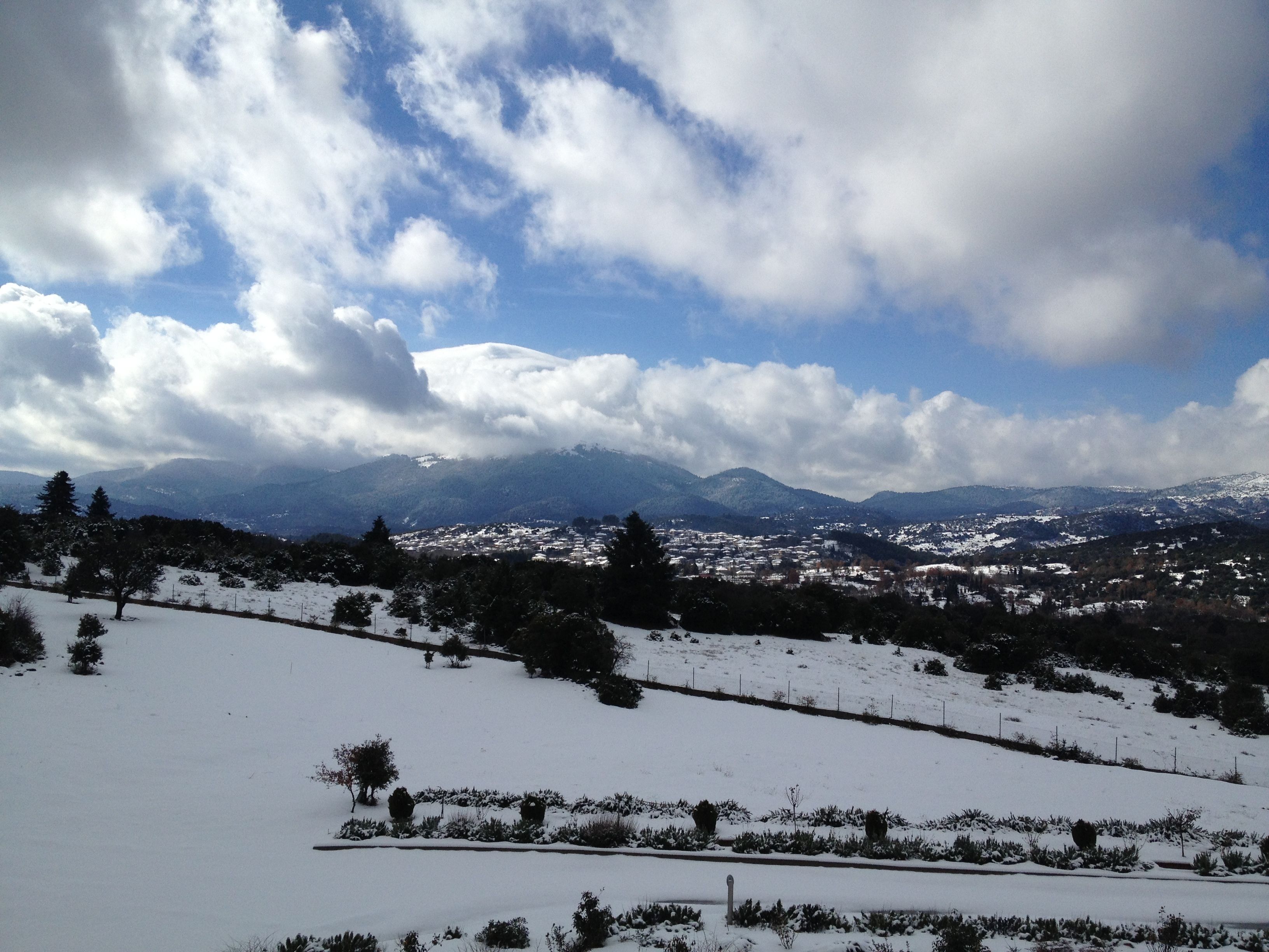 Un paisaje nevado con un pueblo en el valle, montañas al fondo y un cielo despejado.