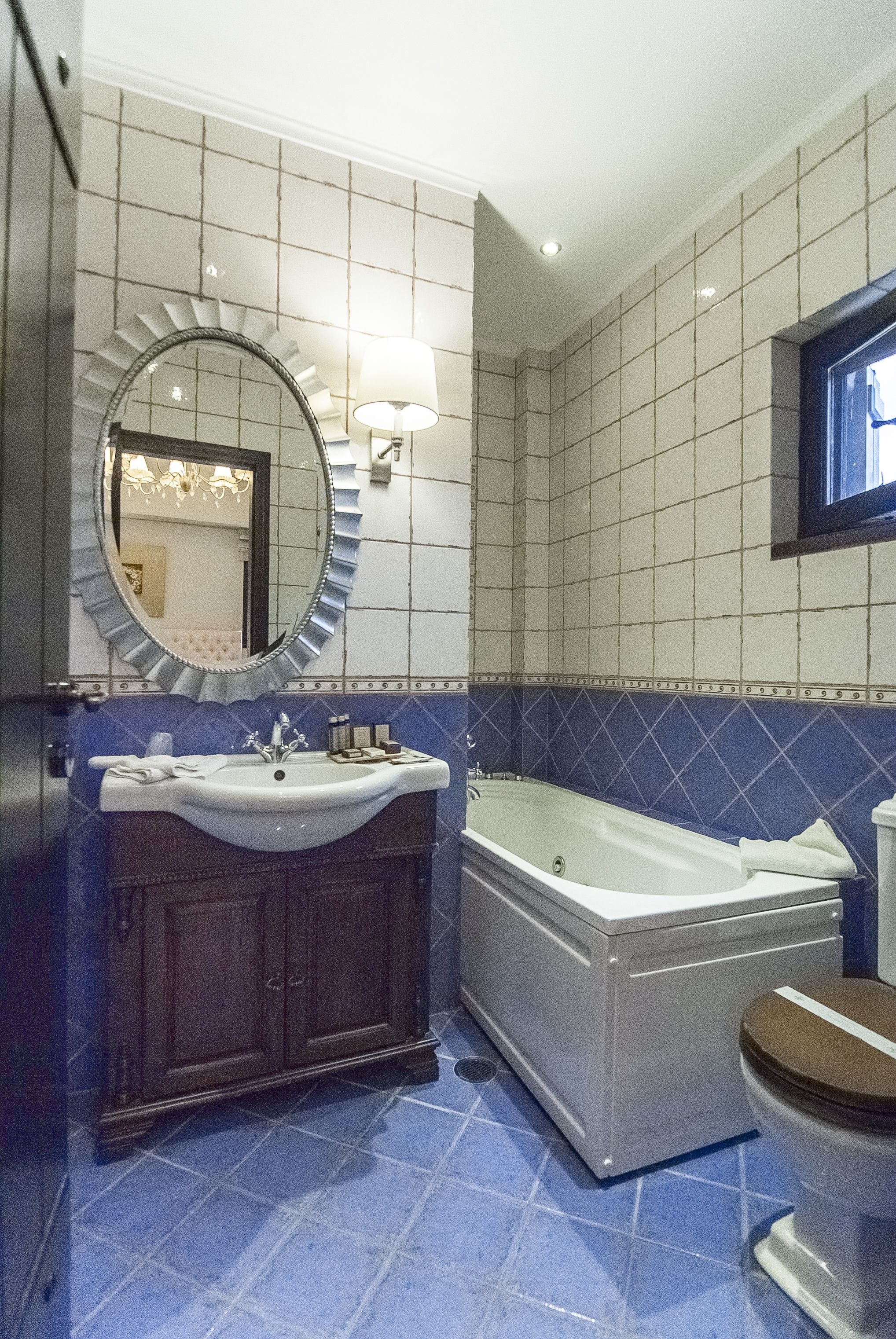 Een badkamer met een wastafel, spiegel, wastafelmeubel, bad en toilet.