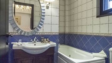 Een badkamer met een wastafel, spiegel, wastafelmeubel, bad en toilet.