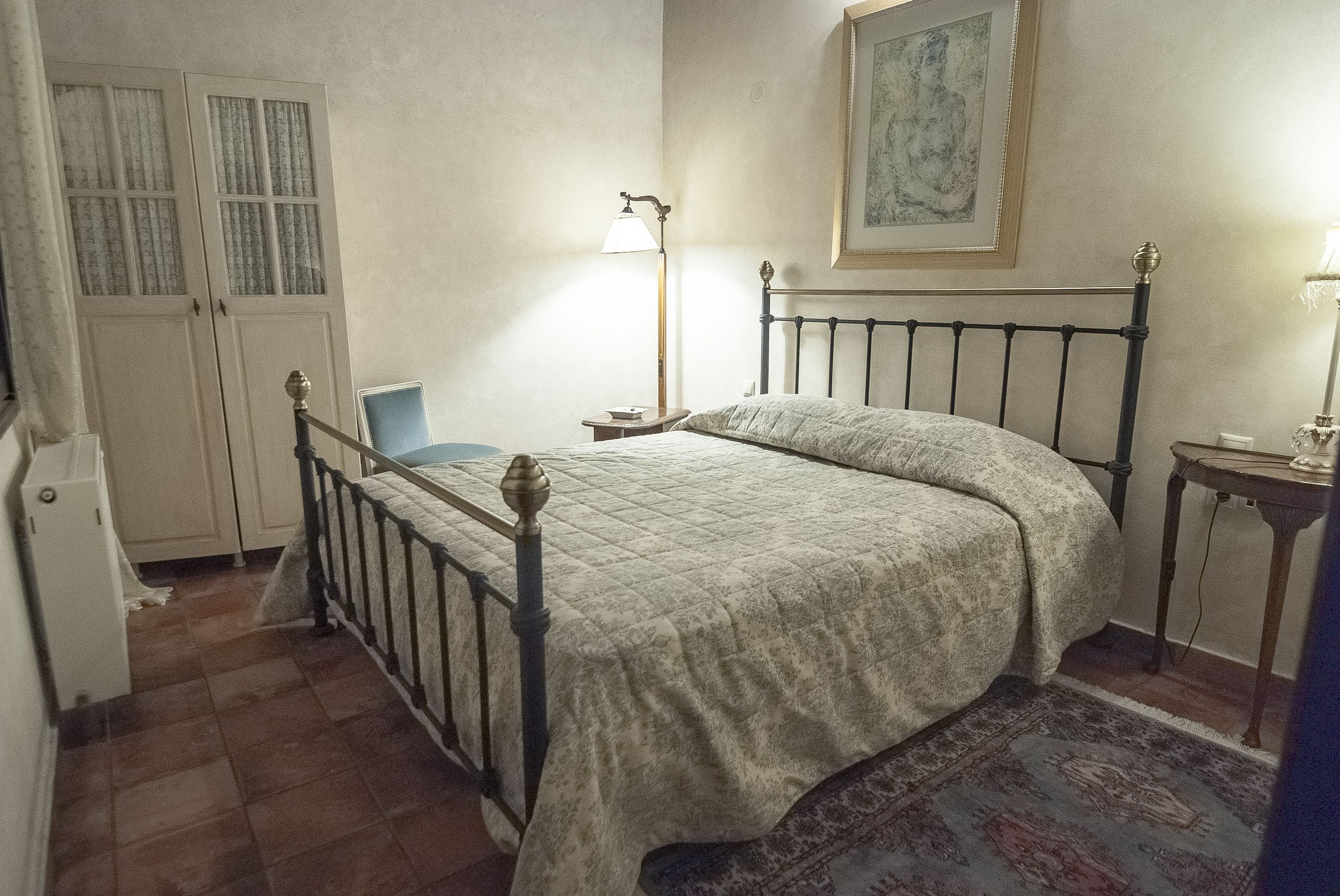 Un dormitorio con una cama, una mesita de noche, una lámpara, una silla y un armario.
