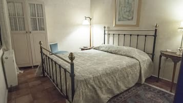 Un dormitorio con una cama, una mesita de noche, una lámpara, una silla y un armario.