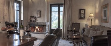 A cozy living room with a fireplace, comfortable seating, and a dining area with a table set for two.