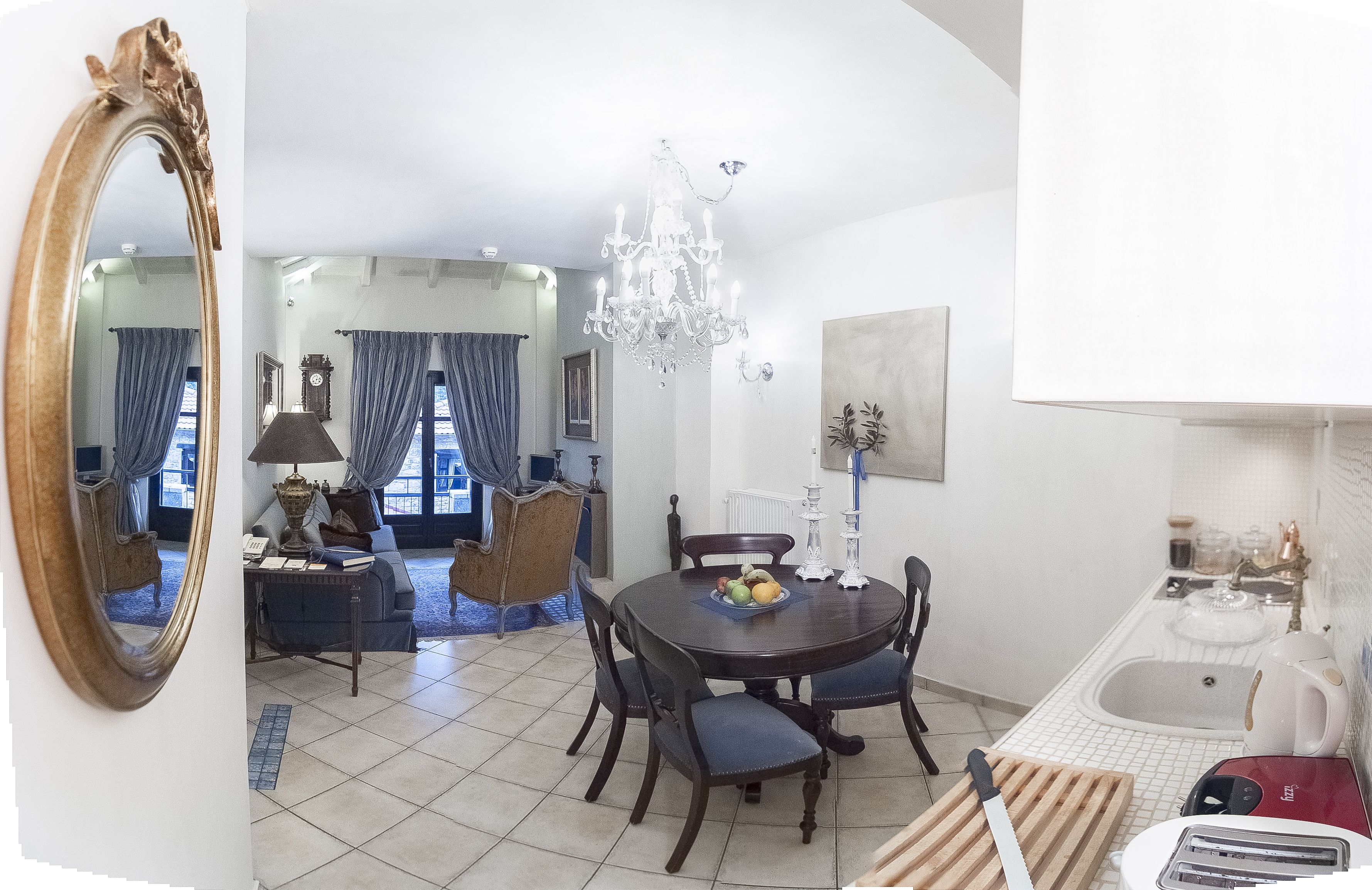 Un'area pranzo con un lampadario, un tavolo rotondo e sedie. C'è un orologio sulla parete e una finestra con tende.