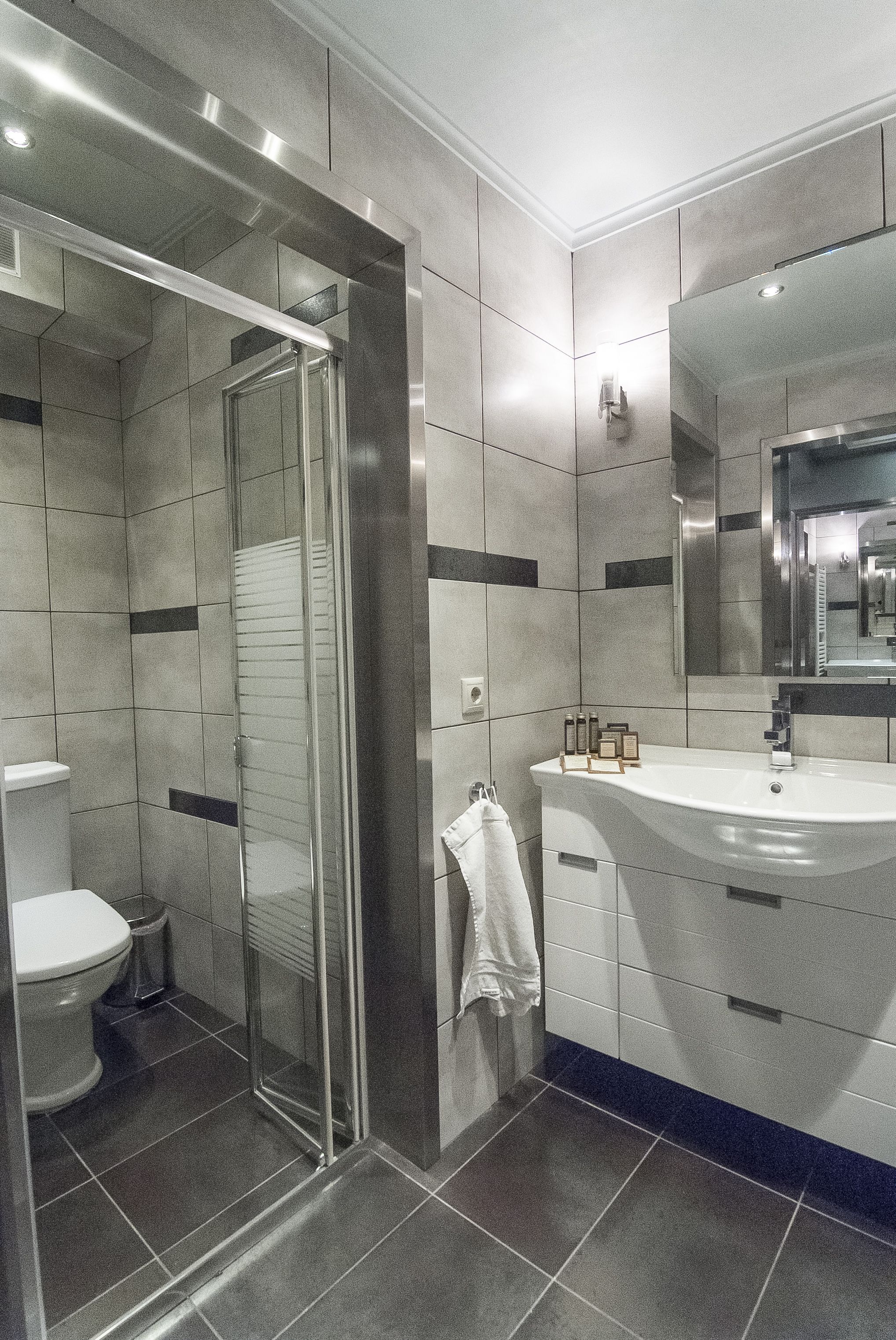 Un baño moderno con cabina de ducha de vidrio, inodoro blanco y tocador con espejo.