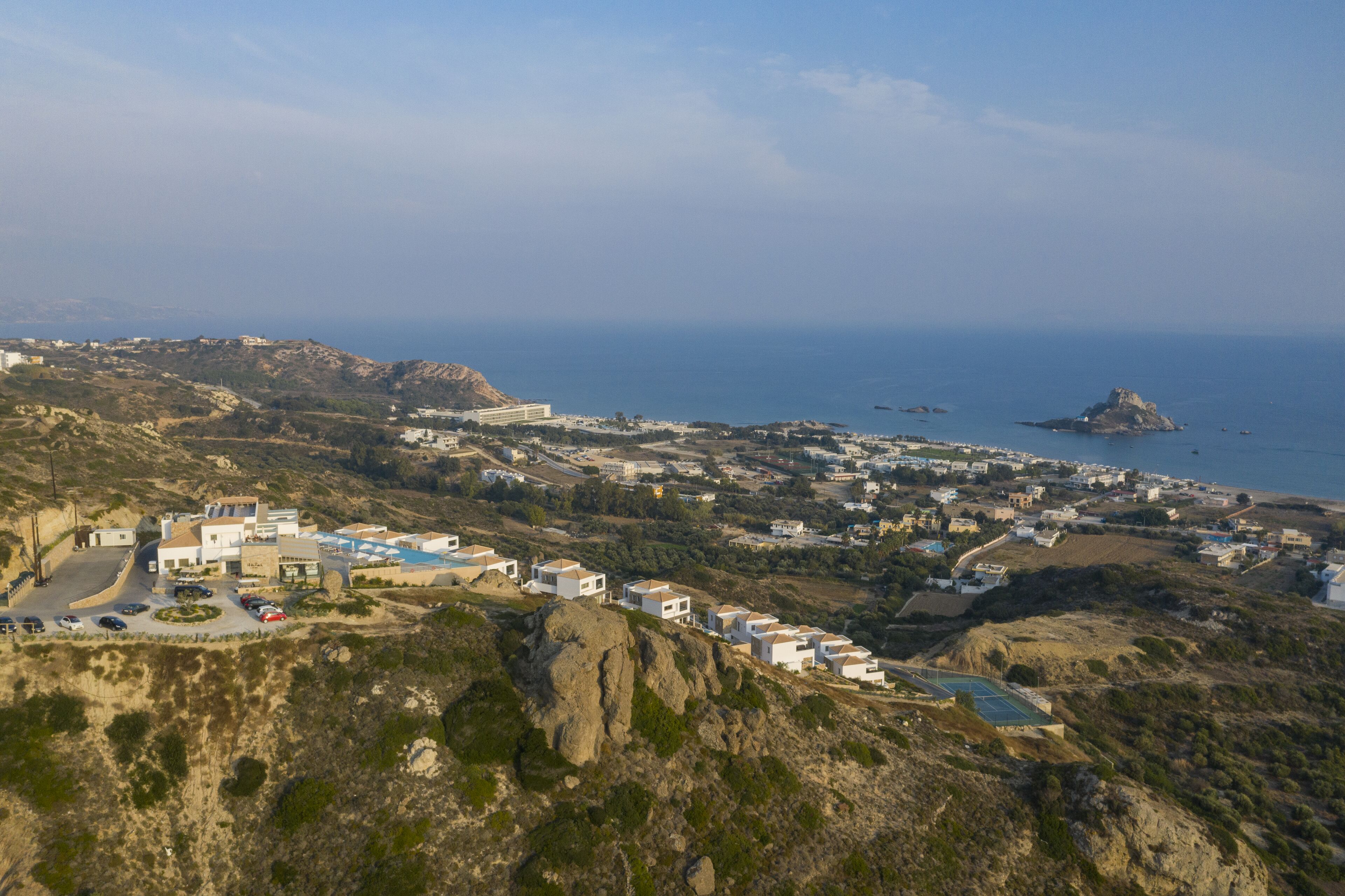 A coastal town with white buildings, a rocky landscape, and a view of the sea.