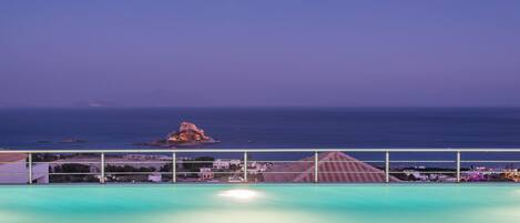 A pool with a view of the sea and a rocky island in the distance.